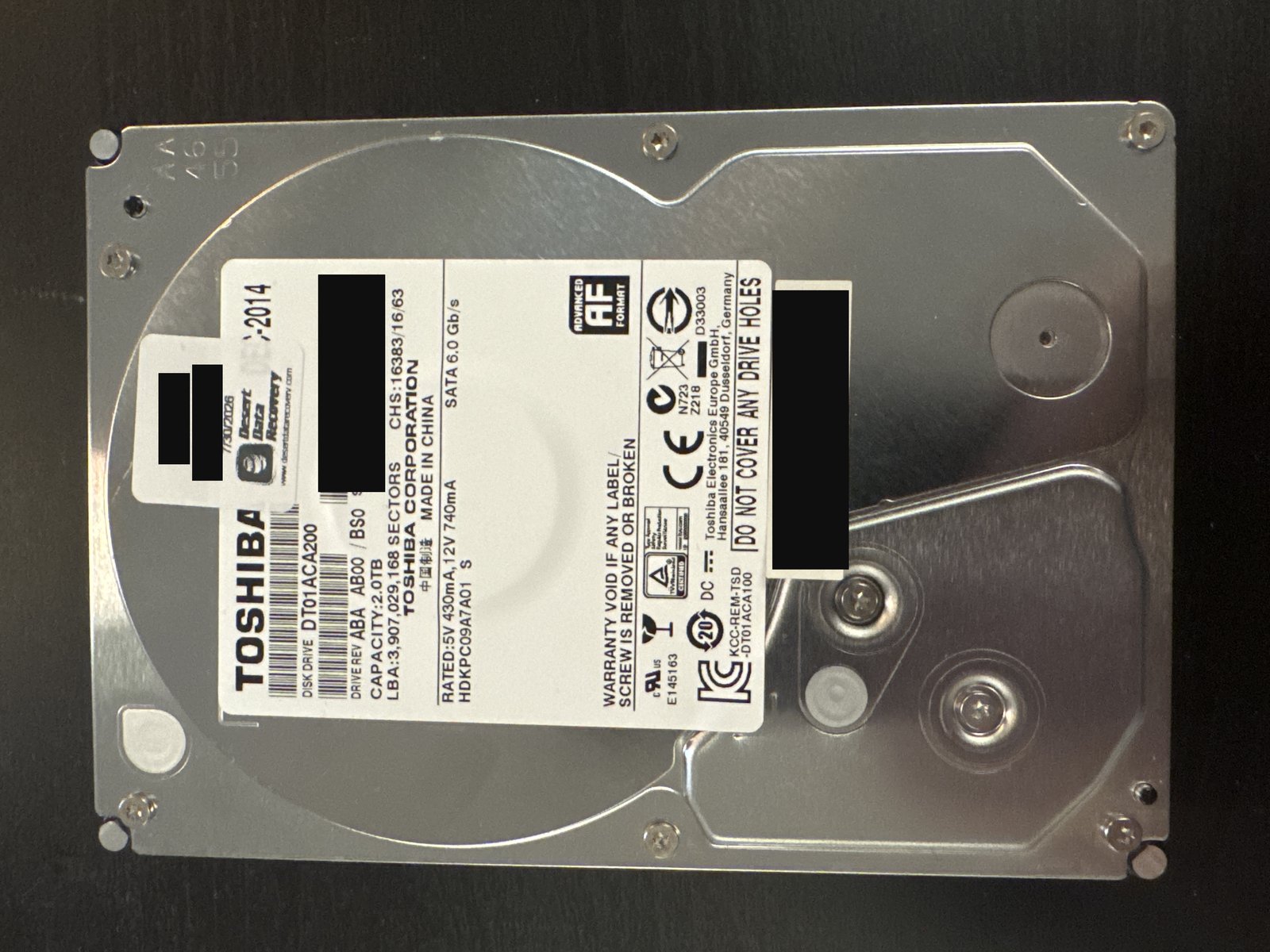 Toshiba DT01ACA200 2 TB SATA hard drive label with serial number and barcodes redacted, and the intake sticker case number and client name blacked out